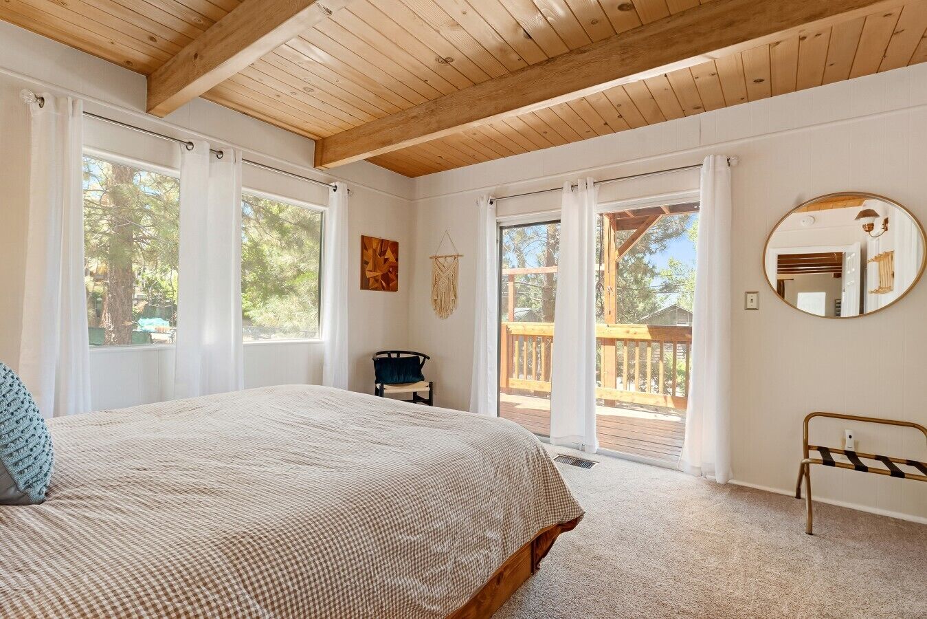 A bedroom with a large bed, a chair, a window, and a balcony.