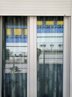 A window with a view of a building with multiple floors and a balcony.