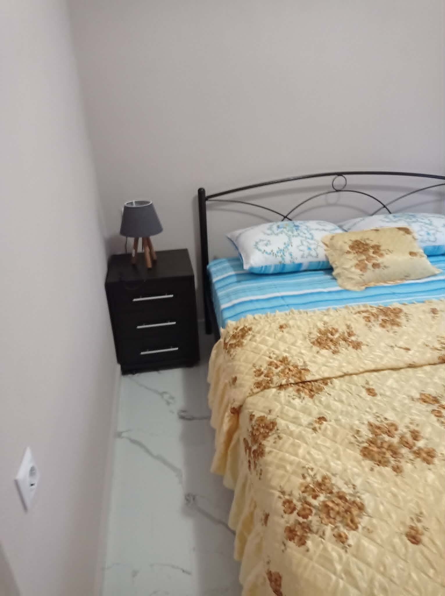 Un dormitorio con una cama, una mesita de noche y una lámpara.