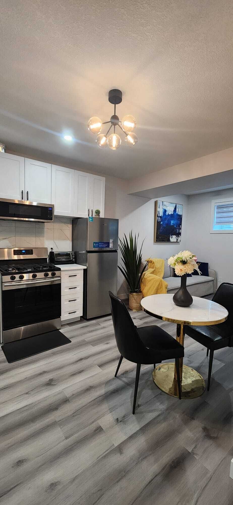 A modern kitchen with a gas stove, oven, microwave, and refrigerator. There is a dining area with a round table and chairs.