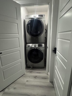 Une buanderie équipée de deux machines à laver à chargement frontal superposées et d’un sèche-linge.