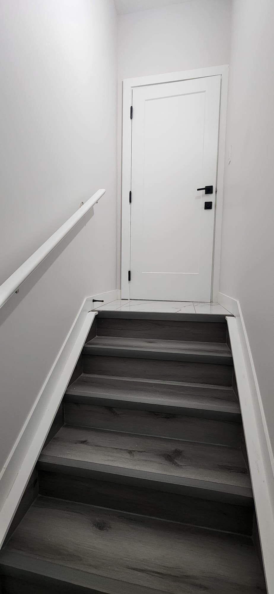 Un escalier surmonté d’une porte blanche, qui donne accès à un espace intérieur.