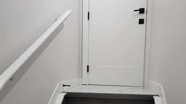 Eine Treppe mit einer weißen Tür am oberen Ende, die zu einem Innenraum führt.