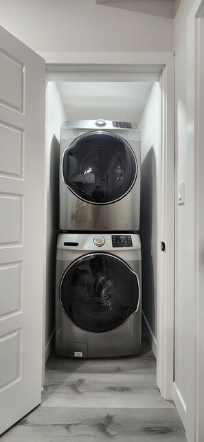 A laundry room with two stacked front-loading washing machines. - Modern Cozy One Bedroom suite Near WEM (Edmonton)