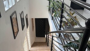 Eine Treppe mit Holzsitzgelegenheiten und Metallgeländern, gesäumt von Blumentöpfen und gerahmten Bildern an den Wänden.