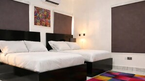 Ein Hotelzimmer mit zwei Betten, einem farbenfrohen Teppich, einer Klimaanlage und einer Wandleuchte.