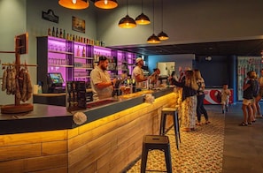 Eine Bar mit Holztresen, Barhocker und einer Auswahl an Flaschen und Gläsern.