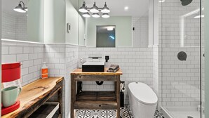 Un baño moderno con tocador de madera, ducha e inodoro.