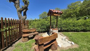 Un espace extérieur rustique aménagé avec des bancs en bois et une structure en pierre portant l’inscription « Del Devore ».