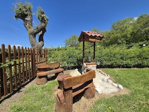 A rustic outdoor seating area with wooden benches and a stone structure labeled 'Del Devore.' - La Baita Del Bosco (Basilicata)