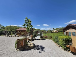 A gravel pathway leading to wooden cabins surrounded by greenery.