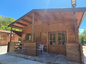 A wooden cabin with a porch, a bench, and a door with glass panels.