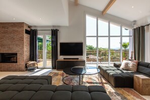Een moderne woonkamer met een open haard, een grote televisie en een zithoek.