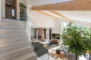 Ein modernes Interieur mit einer Treppe, einem Wohnbereich mit Sofa, Couchtisch und einer großen Pflanze.