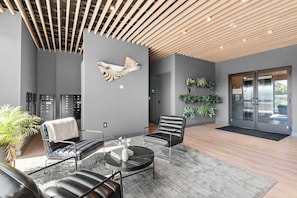 Eine moderne Lobby mit Holzbodenverkleidung, einer Wandskulptur in Fischform, einer Sitzecke mit Ledersesseln, einem runden Tisch und einer Rezeption.