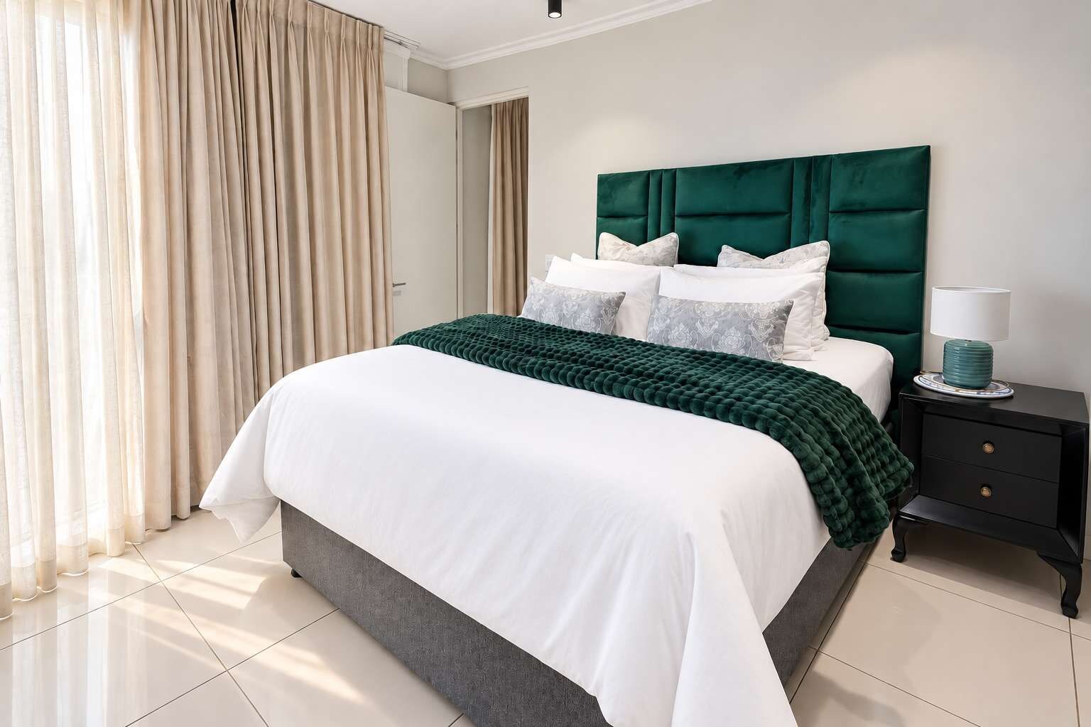 Une chambre d’hôtel avec un lit, une table de chevet, une lampe et une vue sur l’extérieur par la fenêtre.