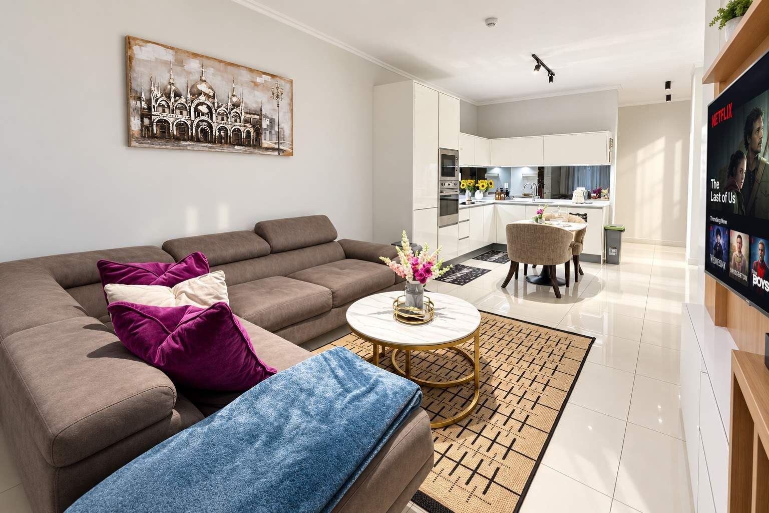 Ein modernes Wohnzimmer mit einer Couch, einem Couchtisch mit einer Vase und einem Essbereich mit Stühlen.
