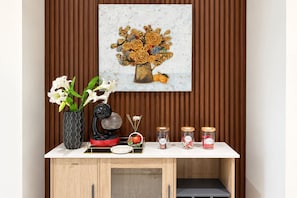 A kitchen counter with a tea kettle, a vase with flowers, and jars of tea and sugar.