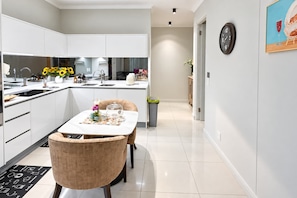A modern kitchen with white cabinets, a dining table with chairs, and a kitchen island.