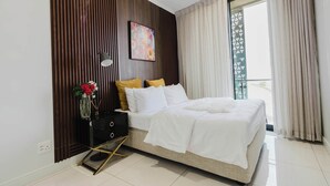 A modern bedroom with a bed, a nightstand, a lamp, and a window with curtains. - The Signature Luxury Stay (Midrand)