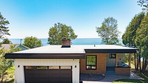 A modern single-story house with a garage, a small porch, and a view of the ocean.