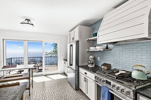 Et moderne køkken med et stort vindue, havudsigt og en balkon med udendørs møbler.