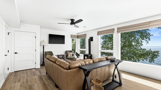 A modern living room with a sofa, a table, a ceiling fan, and a view of the outdoors.