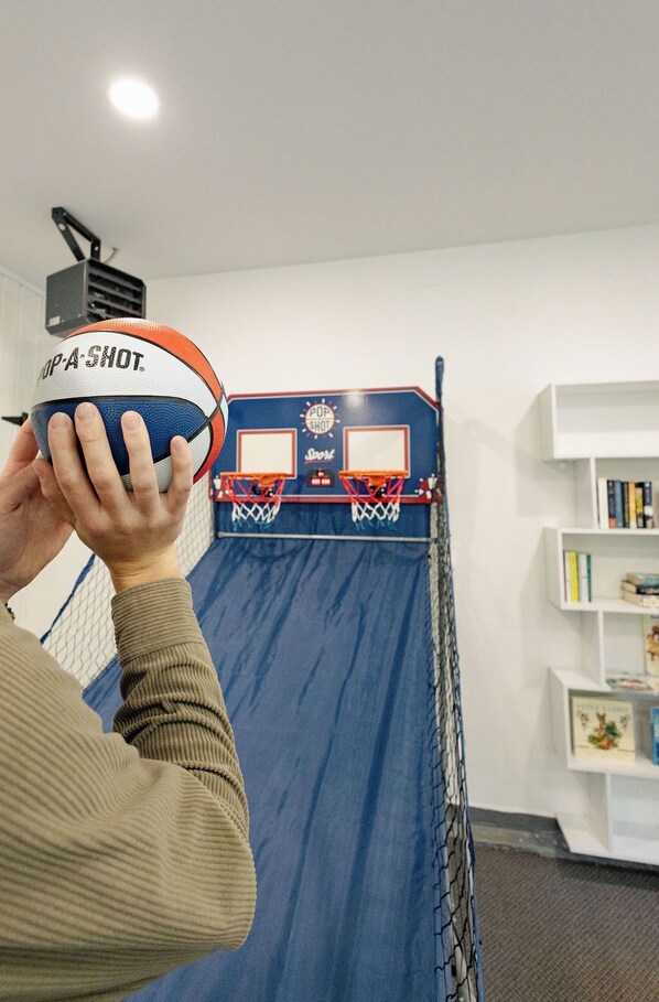 En person holder en basketball foran en miniaturbasketkurv.