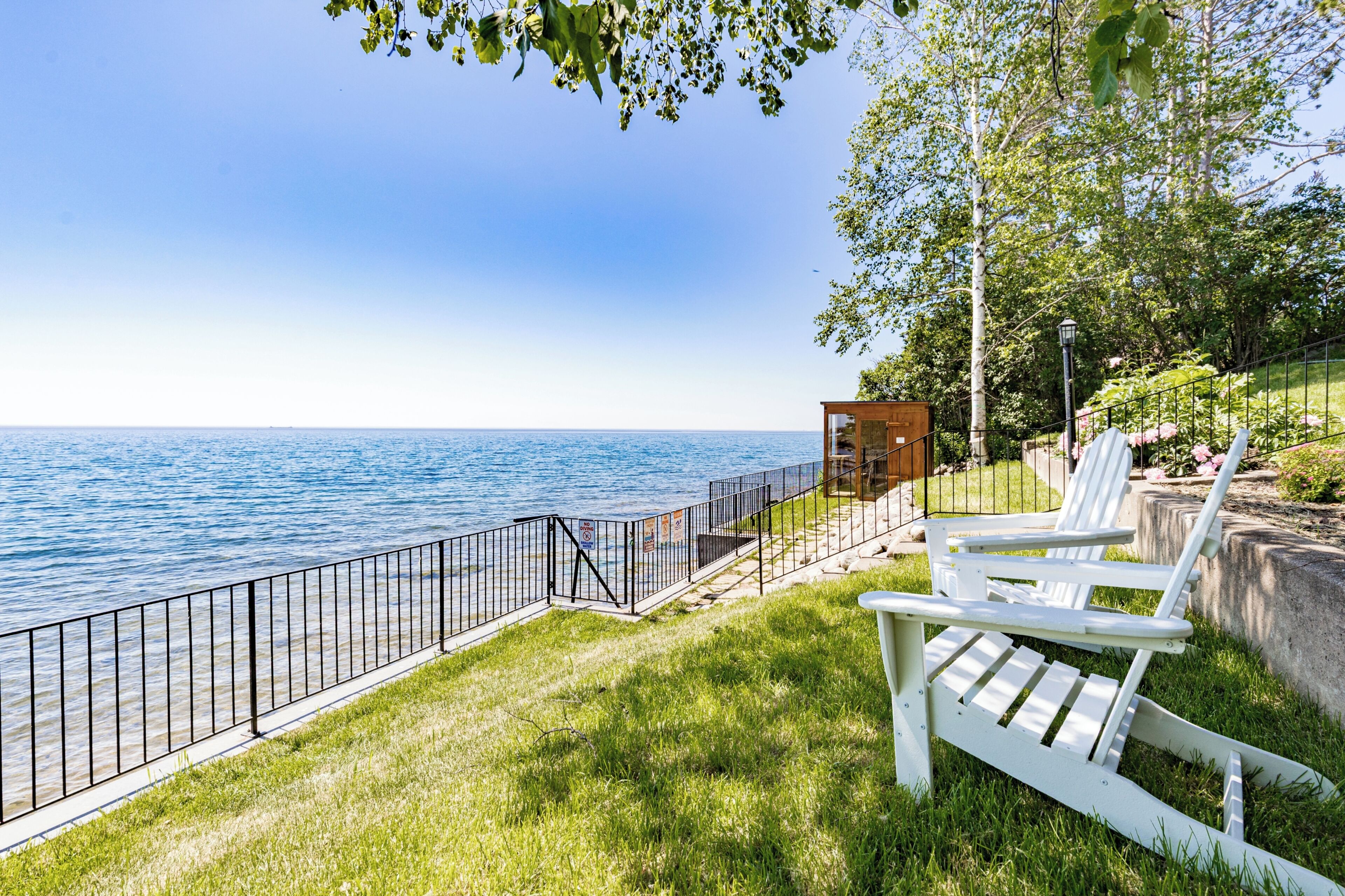 A waterfront property with a grassy area, a wooden structure, and a metal fence.