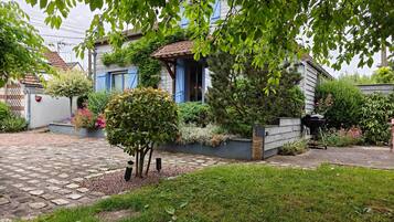 A residential property with a stone pathway, a small tree, and a garden with various plants.