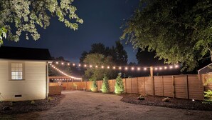 Un camino de grava que conduce a una valla de madera adornada con luces colgantes.