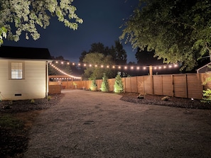 A gravel driveway leading to a wooden fence with string lights. - Retreat with spa and amazing outdoor space. 5 miles to downtown Chattanooga (Rossville)