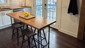 Una cocina con isla de madera, luces colgantes y vistas a través de la puerta.