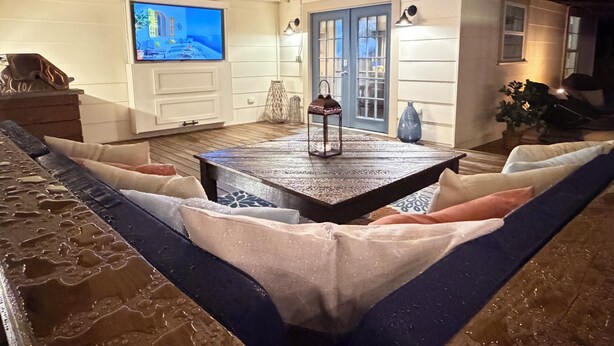 Una sala de estar acogedora con un televisor grande, una mesa de centro de madera y un área de descanso cómoda.