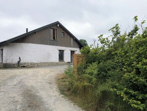 Ein rustikales Bauernhaus mit einer Schotterzufahrt und dichter Vegetation.