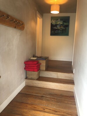 Una escalera de madera con una cesta de cojines rojos y un cuadro en la pared.