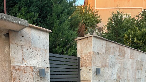 A gated entrance with a potted plant, stone walls, and a tiled pavement. - Riverside Luxury 3-bedroom apartment in beautiful Štip (Štip)