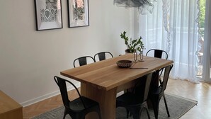 A dining area with a wooden table, black chairs, a potted plant, and two framed artworks on the wall. - Riverside Luxury 3-bedroom apartment in beautiful Štip (Štip)