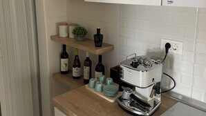 A kitchen with a wooden countertop, wine bottles, a coffee machine, and a dish rack. - Riverside Luxury 3-bedroom apartment in beautiful Štip (Štip)