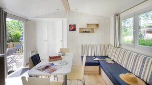 Ein kompakter Wohnraum mit Essbereich, einer Sitzecke mit gestreifter Couch und einem kleinen Tisch mit Zeitschrift und Snacks.