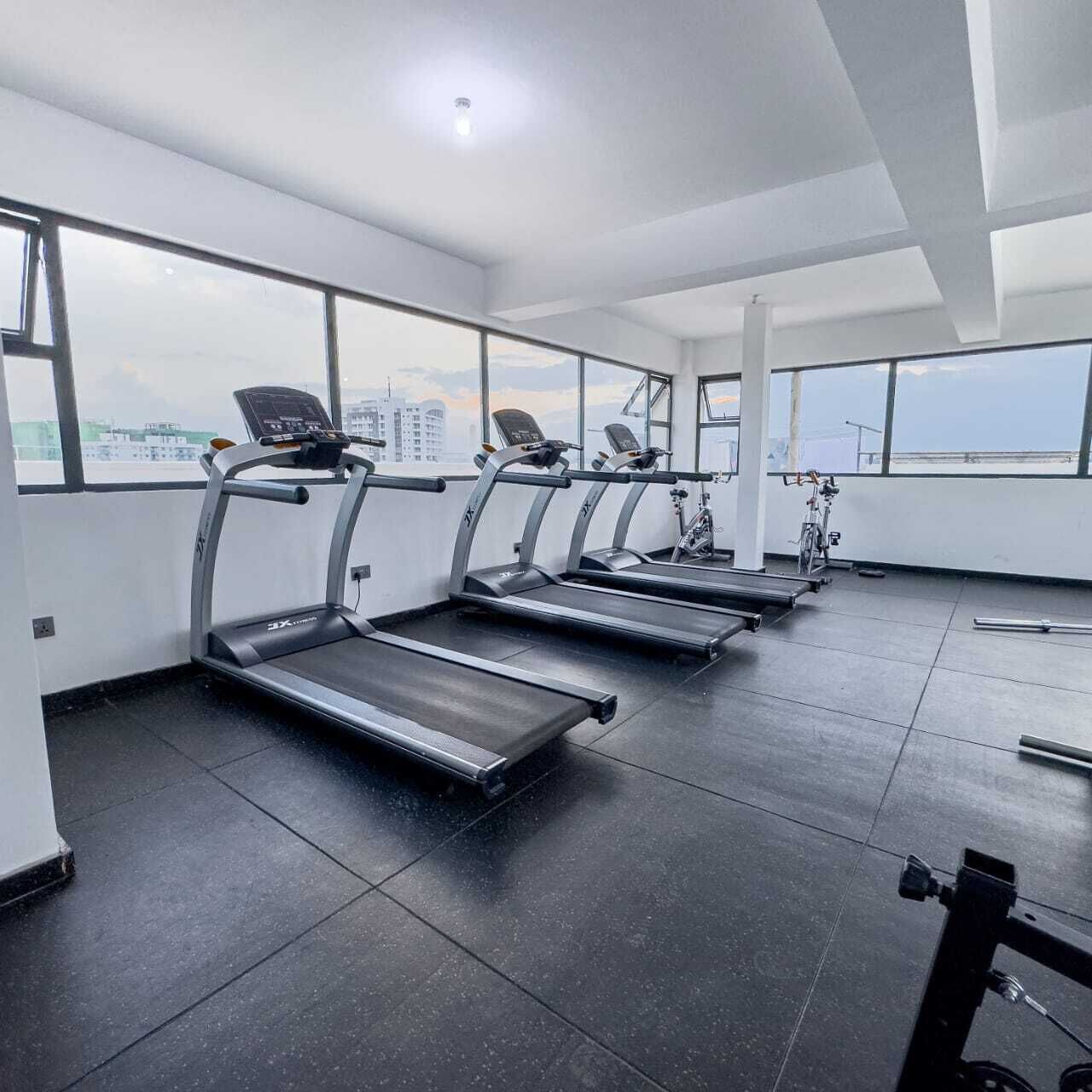 Ein Fitnessstudio mit Laufbändern, einem Ergometer und einem Rudergerät.