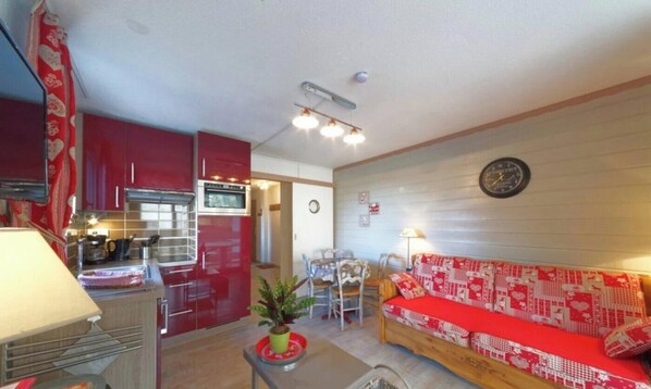A compact living space with a kitchenette, a dining area, and a sofa.