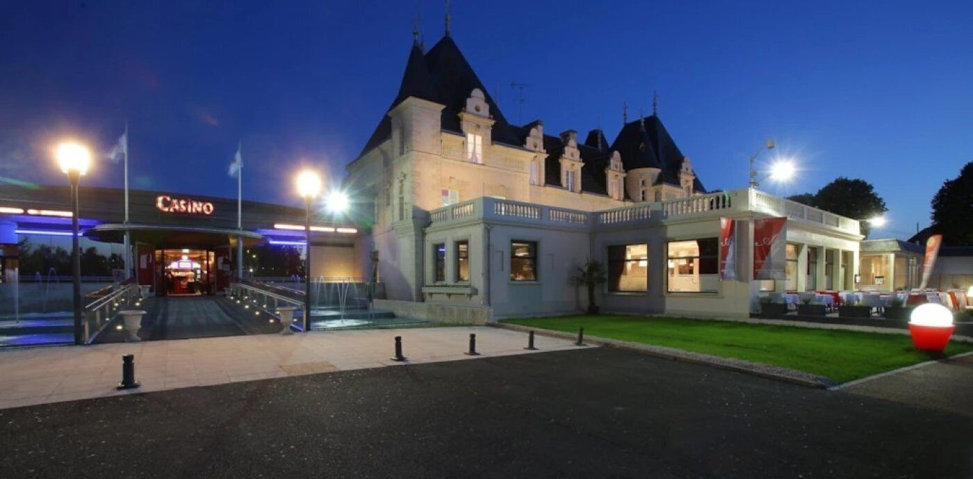 Un edificio grande con entrada al casino, una escalera monumental y una fachada bien iluminada.