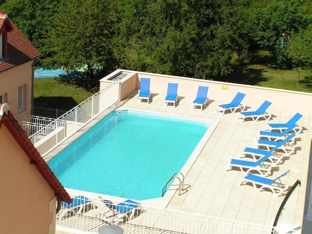 En swimmingpool med blå liggestole og et hvidt hegn.