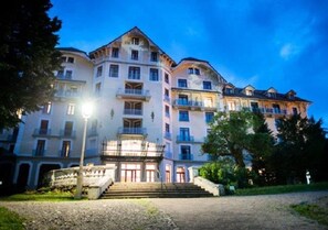 A multi-story hotel with a central courtyard, balconies, and a staircase leading to the entrance. - Appartement 3 étoiles - ccbgfdc (Allevard)