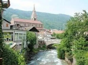 A river flowing through a town with a bridge, buildings, and a church spire. - Appartement 3 étoiles - ccbgfdc (Allevard)