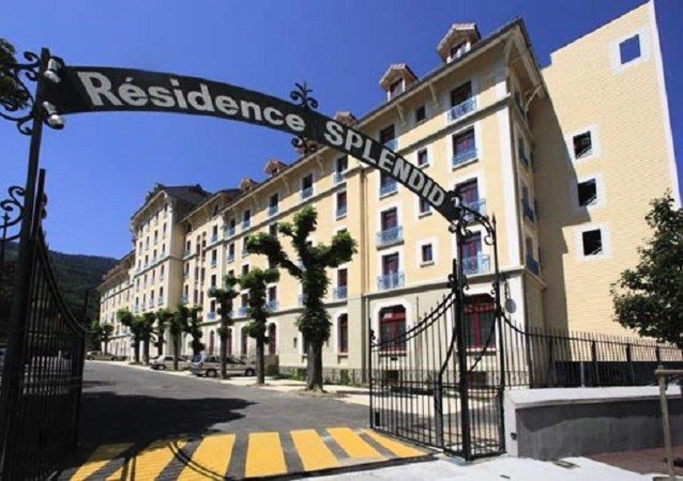 A residential building with a gated entrance, multiple floors, and balconies.