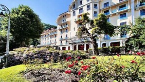 A multi-story hotel with balconies, a garden with flowers, and a clear blue sky. - Appartement 3 étoiles - ccbgfdf (Allevard)