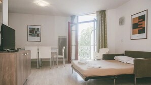 Ein Hotelzimmer mit Bett, Schreibtisch, Stuhl, Fernseher und einem Balkon mit Blick.