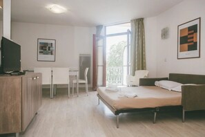 Ein Hotelzimmer mit Bett, Schreibtisch, Stuhl, Fernseher und einem Balkon mit Blick.
